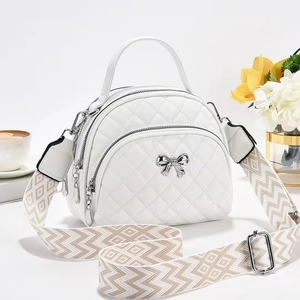 White quilted semi-circular handbag with silver bow detail and patterned wide strap