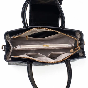Vue de dessus d'un sac en cuir verni noir montrant plusieurs compartiments et zips dorés