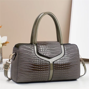 Sac à main vert grisâtre avec gaufrage crocodile et bandoulière dans un décor épuré