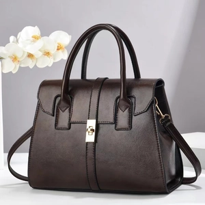 Elegant dark brown leather handbag with gold metal lock and shoulder strap