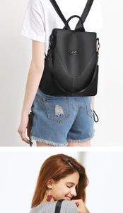 Détail du sac à dos antivol noir montrant le logo kangourou et les surpiqûres