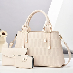 Close-up of three-piece cream tote set with woven pattern and golden metal hardware