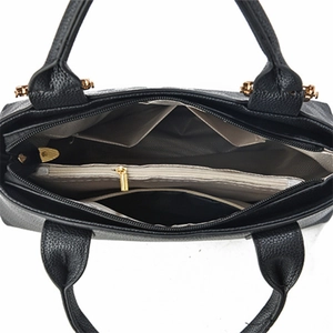 Top view detail of the black leather tote bag featuring a multi-compartment interior