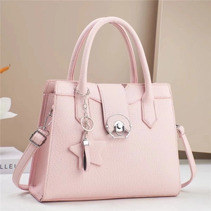 Detail of pink lychee leather handbag with metal rotary lock and star charm accent