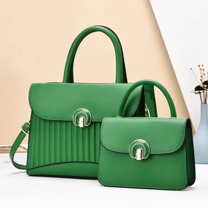Détail de sacs à main verts avec plis verticaux et fermoirs métalliques dorés chic