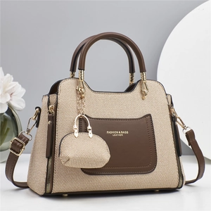 Sac à bandoulière chic en tissage beige avec détails en cuir marron et mini pendentif