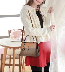 Chic brown leather handbag with lychee texture and adjustable strap worn by a model