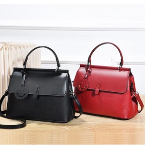 Detail of leather handbags in black and red with lychee texture and smiley charms