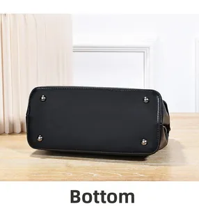 Detailed bottom view of black tote bag featuring four protective metal rivets on leather