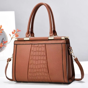 Close-up of brown tote bag with crocodile pattern panels and gold hardware details