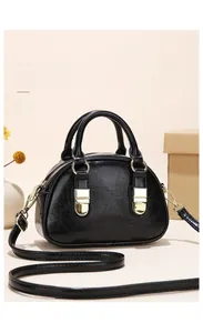 Detail of black semi-circular PU leather handbag with golden charms and texture