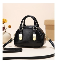 Detailed close-up of a mini black crossbody bag with gold hardware in a home setting