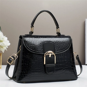 Detail of elegant black crocodile pattern handbag with golden D-clasp and leather texture