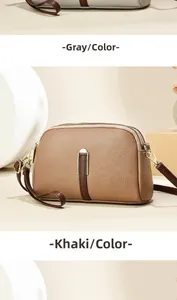Detail van de crossbodytas van generfd leer in grijs en kaki met dubbele ritsen