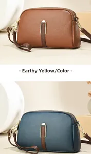 Detail van crossbodytas van generfd leer met dubbele ritssluiting en gouden hardware