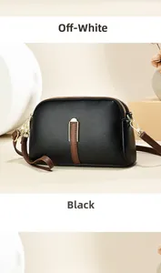 Detail van zwarte crossbodytas van generfd leer met goudkleurige U-vormige hardware en riem