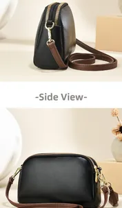 Detail van zwarte kiezellederen crossbodytas met dubbele rits en gouden fittingen