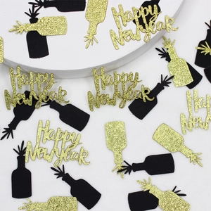 Close-up of Happy New Year glitter confetti with champagne bottle cutouts on white surface