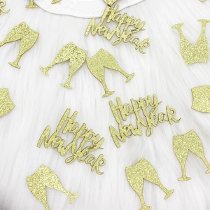 Close-up of golden glitter Happy New Year and champagne cup confetti on white fur