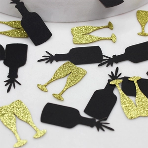 Macro shot of black wine bottle and gold glitter glass confetti for party table decor