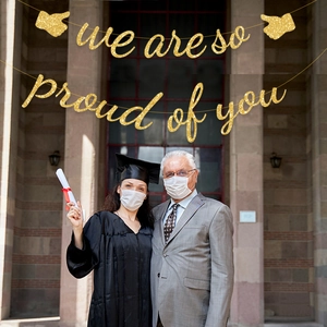 Glittery gold 'We are so proud of you' graduation banner decoration for outdoor ceremonies