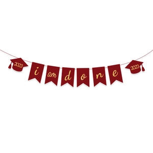 Close-up of maroon graduation banner with gold glitter I AM DONE text and 2023 caps