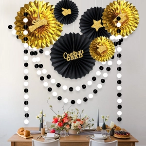 Detail of black and gold paper fan set with Congrats GRAD banner for graduation party decor