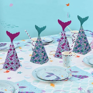 Mermaid party favor boxes with glitter fish tails and blue scale pattern on a table