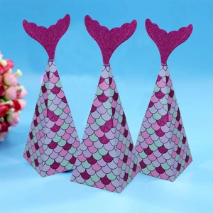 Mermaid party favor boxes with glitter tails and colorful fish scale pattern on blue background