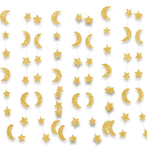 Detailed view of glittering gold star and moon party garlands hanging on white background