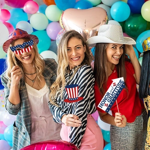 Drei Frauen posieren mit USA-Unabhängigkeitstag-Party-Requisiten und bunten Ballons