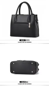 Detailed view of the back zipper pocket and gold protective metal feet on a black tote bag