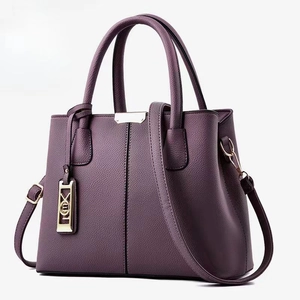 Detail of dark purple litchi grain leather tote bag with gold hardware and logo tag