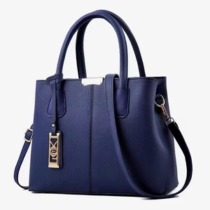 Detail of navy blue pebble leather handbag with gold metal hardware and stitching