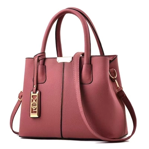 Detail of dusty rose litchi grain leather bag with golden hardware and logo tag