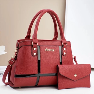 Detail of red lychee textured leather tote bag and matching clutch with gold hardware
