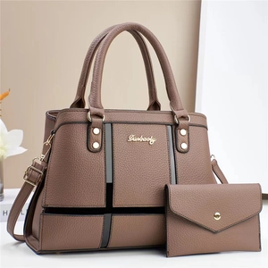 Detail of dark brown tote bag set with pebble leather texture and gold metal logo