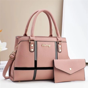 Close-up of pink pebbled leather handbag set with geometric black trim and gold hardware