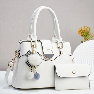 Détail d'un ensemble sac à main et portefeuille blancs avec boucles dorées et breloque