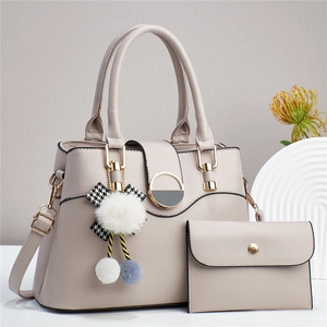 Elegant beige two-piece women's handbag set with pom-pom charm and matching wallet