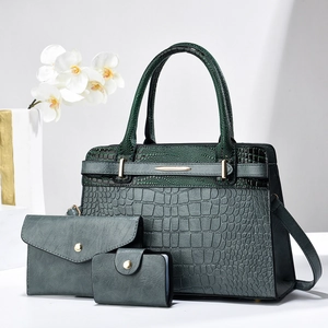 Detailed view of dark green crocodile pattern three-piece handbag set with gold hardware