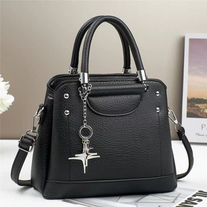 Close-up of black lychee grain leather handbag with silver hardware and star pendant