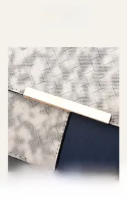 Close-up of woven fabric and navy litchi leather texture with a gold metal clasp