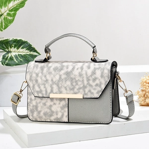 Gray woven texture crossbody bag with gold hardware on a clean minimalist display