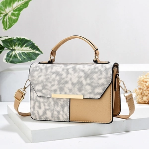 Crossbody bag with contrast stitching and metallic gold accents on geometric stand
