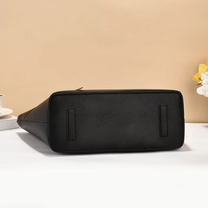 Detail view of the black tote bag bottom with litchi grain texture and reinforced pads