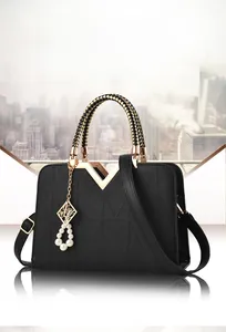Detail of black embossed handbag with gold V-trim and pearl pendant accessory