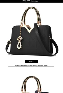 Detail of black faux leather handbag with V-shaped gold metal hardware and woven handle