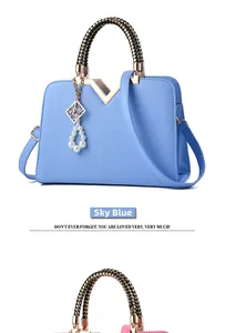 Detail of light blue handbag with geometric pattern, woven handle and gold V-clasp