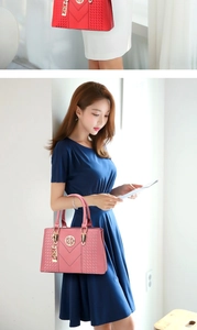 Detail of red and pink trapezoid handbags with lychee texture and gold metal logo